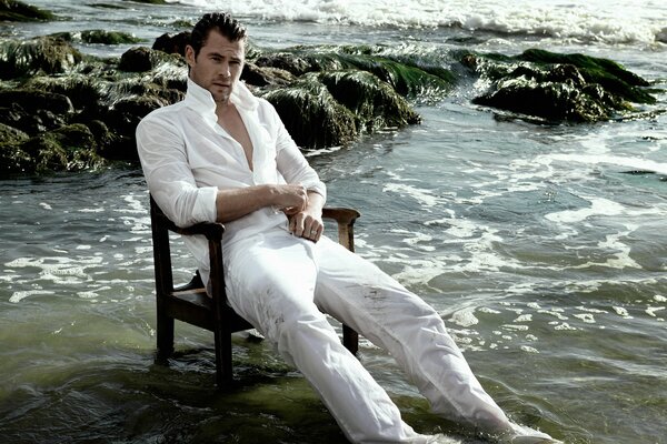 Chris Hemsworth actor sitting on a chair in the water wet in a white suit resting