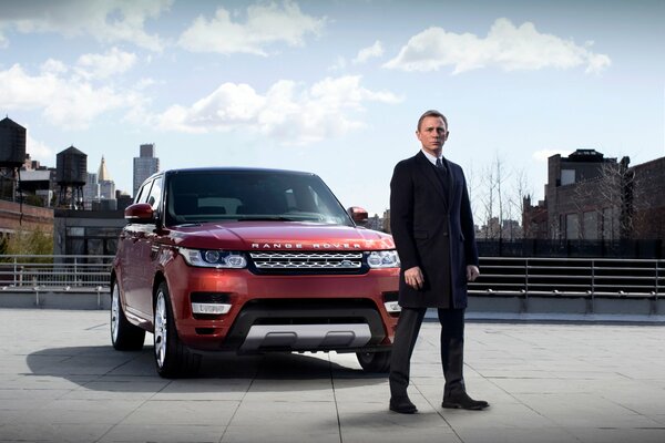 Daniel Craig dans le rôle de James Bond à côté de la voiture