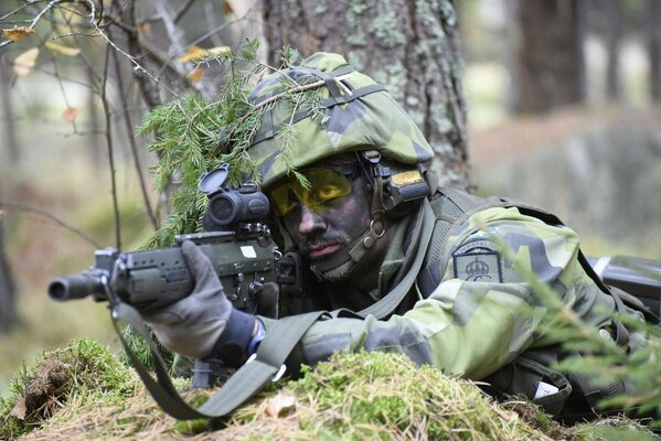 A soldier in the Swedish army is lying on the ground