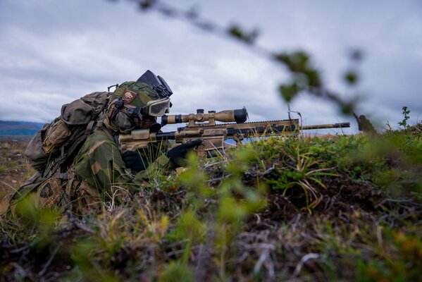 Sniper assis dans la tranchée tient le fusil prêt