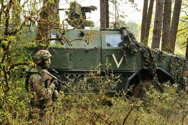 Un soldado está parado cerca de un vehículo de combate