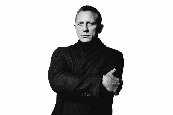 Attore Daniel Craig in un cappotto nero su sfondo bianco