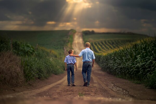 Idący przez pola uprawne syn i ojciec