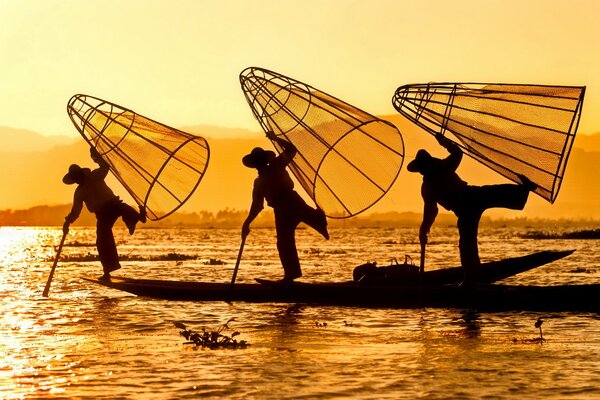 Siluetas de pescadores en el río al amanecer