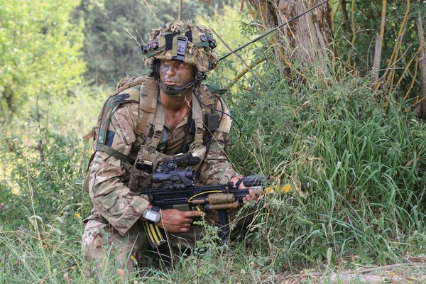 Soldat en camouflage se cache dans les buissons avec des armes