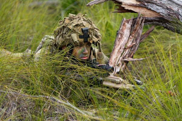 A soldier with a gun in an ambush disguised