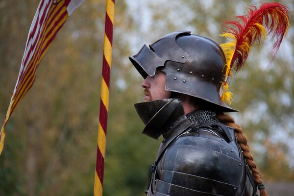 A knight in metal armor with a feather on his helmet