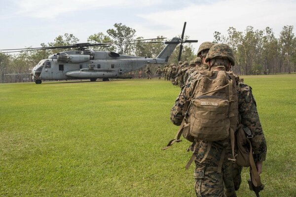 Soldiers in uniform walk across the green grass to the Boeing