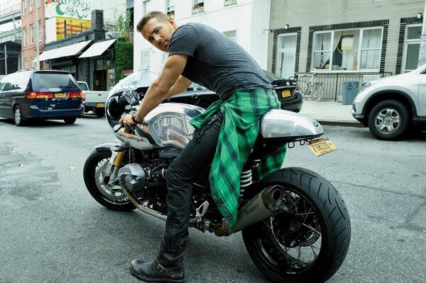 A guy in a gray T-shirt is sitting on a motorcycle