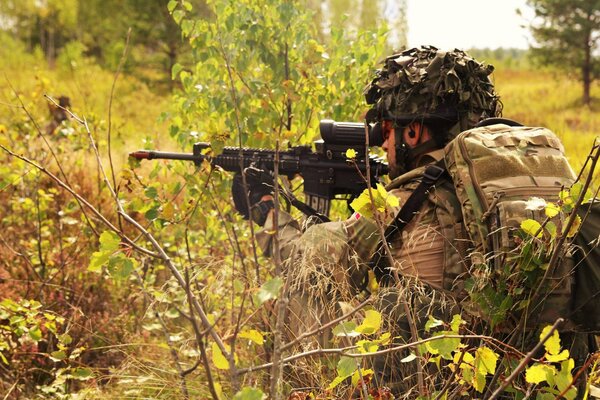 A soldier of the Danish army is sitting in ambush in the bushes