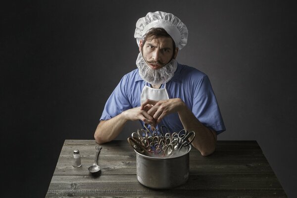 Un uomo in costume da barbiere si siede a un tavolo di legno davanti a una padella con le forbici