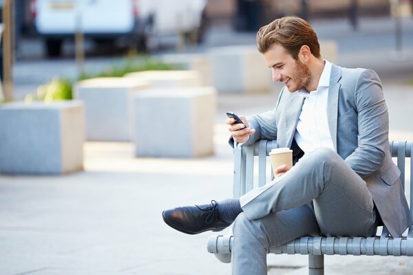 A businessman reads a message on his phone and smiles