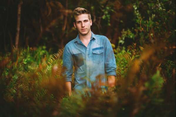 A man in a denim shirt in the woods