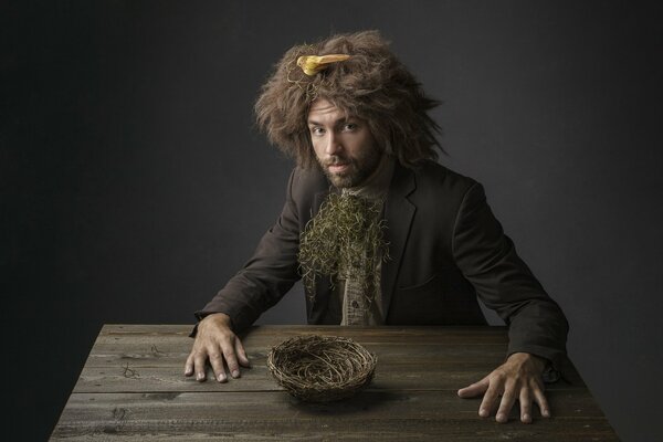 An unusually dressed man sitting at a wooden table