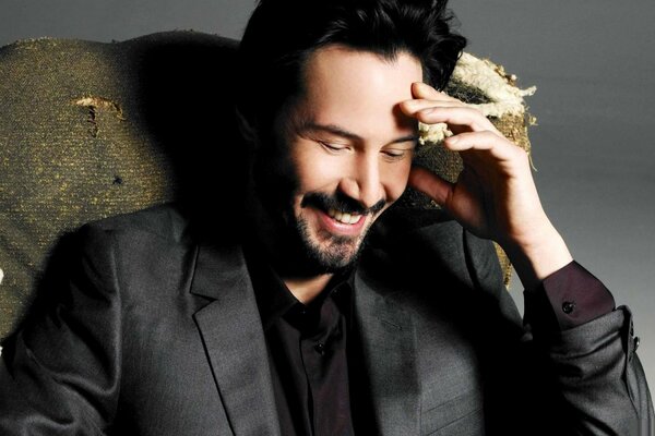 Keanu reeves im Anzug auf einem stuhl