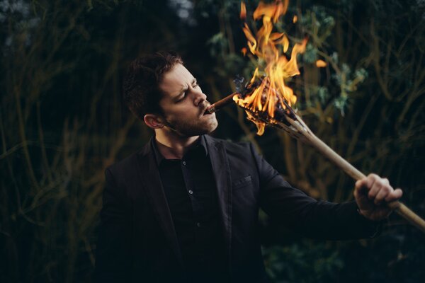 The guy lights a cigarette from the fire from a branch