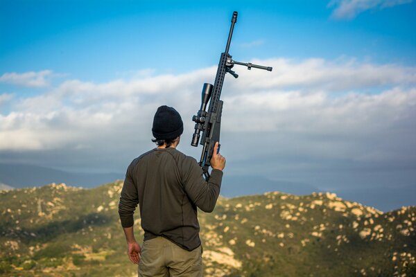 Mann steht mit Gewehr von hinten