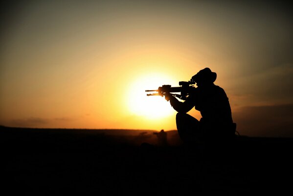 Silhouette d un soldat avec une mitraillette au coucher du soleil