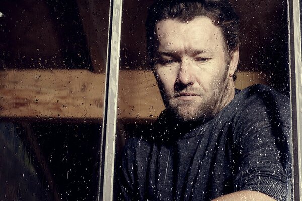 Nachdenklich und traurig joel edgerton am fenster mit Regentropfen