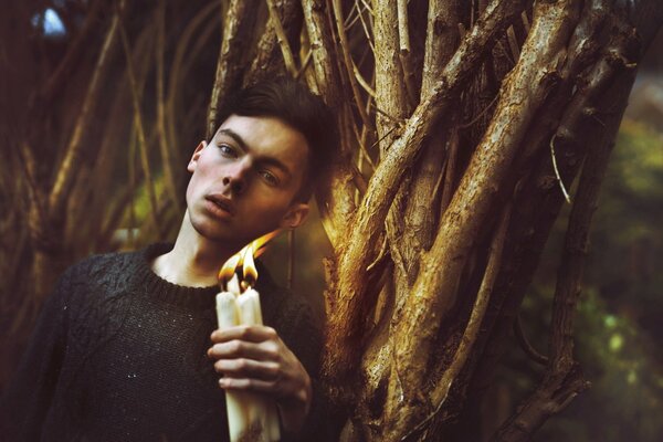 Fotoshooting im Wald eines Kerls mit Kerzen