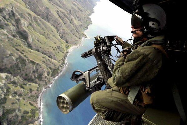 Soldado con ametralladora en helicóptero en el aire