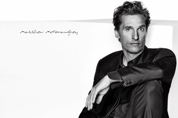 Matthew McConaughey sits in a black suit