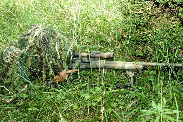 Francotirador en komuflage en la hierba verde