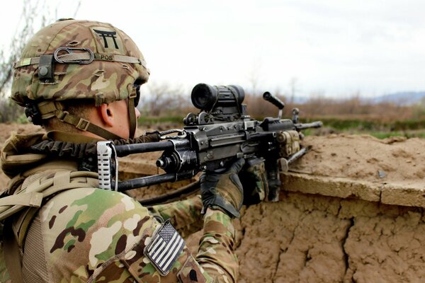 Ein Soldat mit einer Waffe sitzt in einem Versteck