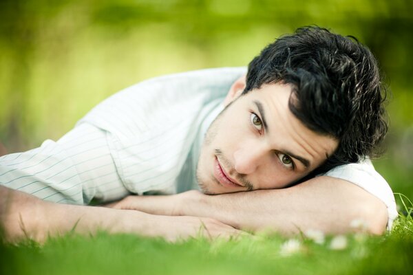 Le gars se trouve sur l herbe et regarde dans l OBJEKTIV