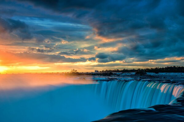 Wasserfall-Landschaft mit dichten Wolken am Sonnenuntergang Hintergrund