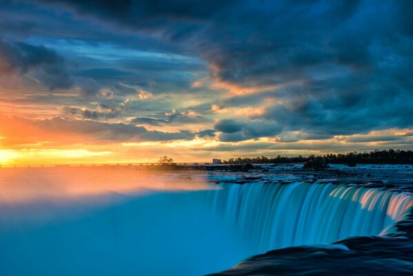 Paisaje de cascada con densas nubes en el fondo de la puesta de sol