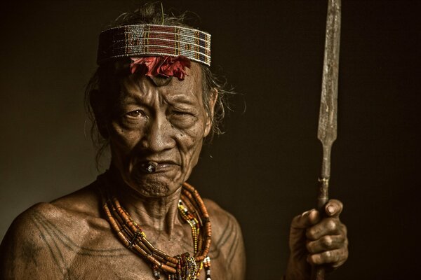 A dark-skinned old Indian holds a spear