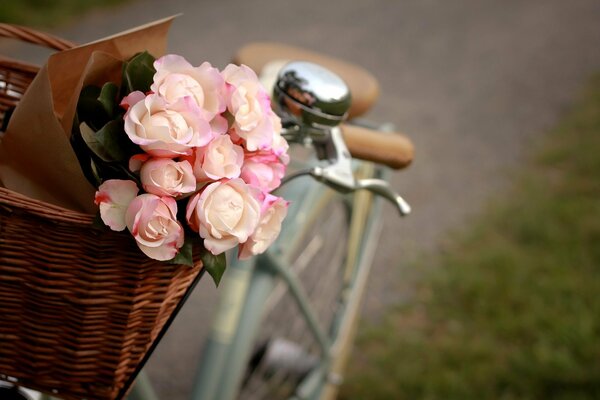 Ein Strauß rosafarbener Blumen liegt in einem Korb, der auf einem Fahrrad steht