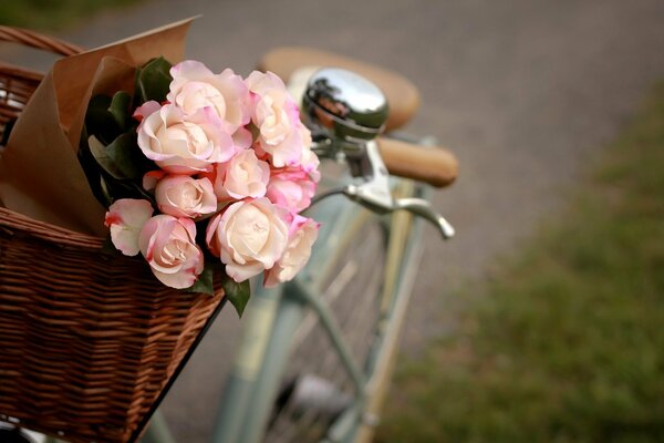 A bouquet of pink flowers lies in a basket standing on a bicycle