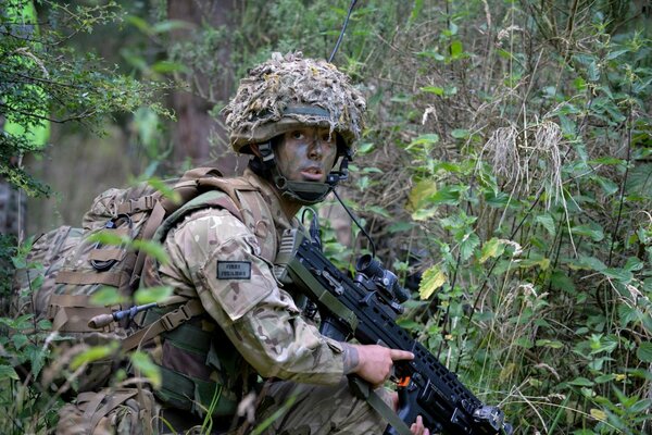 Soldat avec des armes se faufile à travers la forêt sauvage