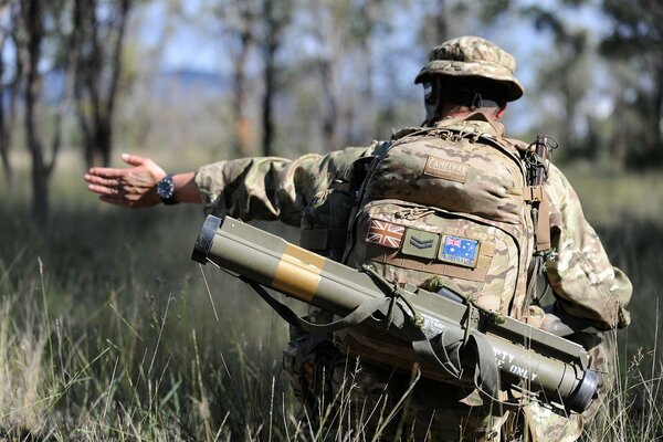 A soldier with a weapon in the army, from the back