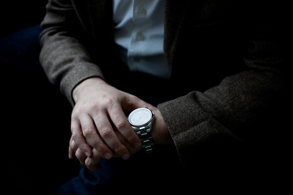 El hombre de la chaqueta Mira el reloj de pulsera, determina la hora