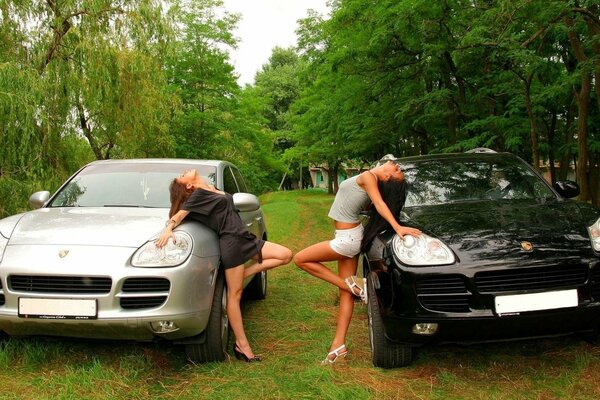 Dos chicas posando cerca de dos coches