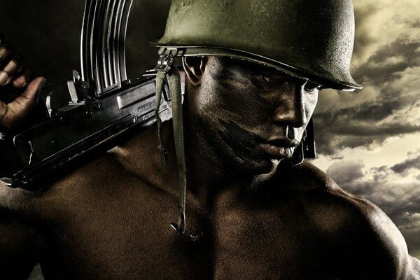 A dark-skinned man in a helmet with a machine gun