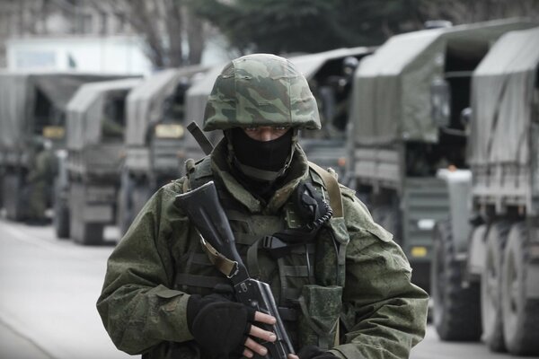 A military man in a balaclava helmet with a machine gun