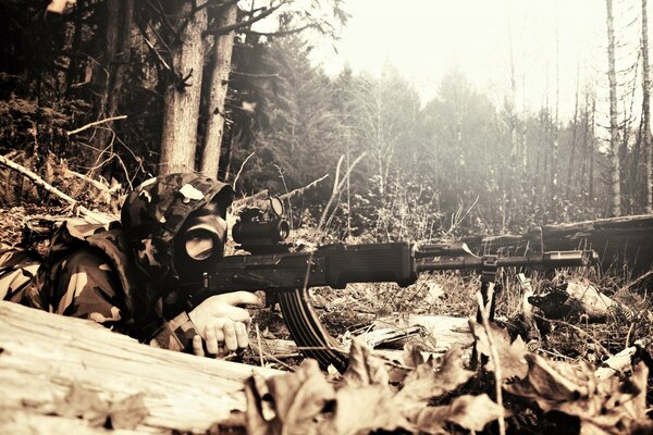 A military man in a gas mask is sitting in ambush