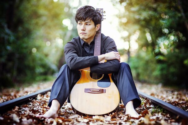 Le gars sur les rails avec une guitare pense à quelque chose