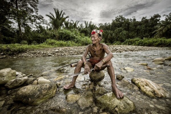 A soldier sits with a gun on the river