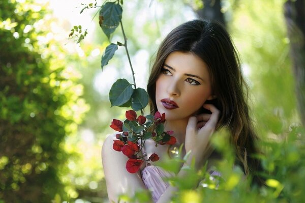 Brunette with a flower in the thicket of the forest