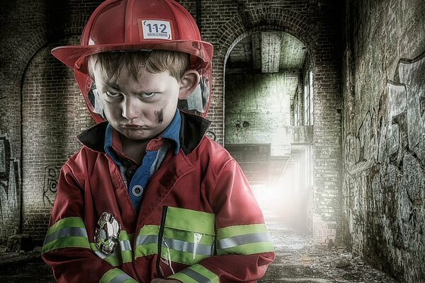 Mały Smutny chłopiec w mundurze przeciwpożarowym