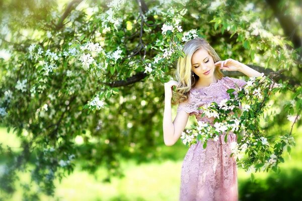 A girl in a pink dress next to a flowering tree