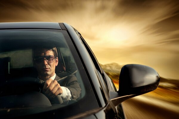 A man is driving at high speed in a black car