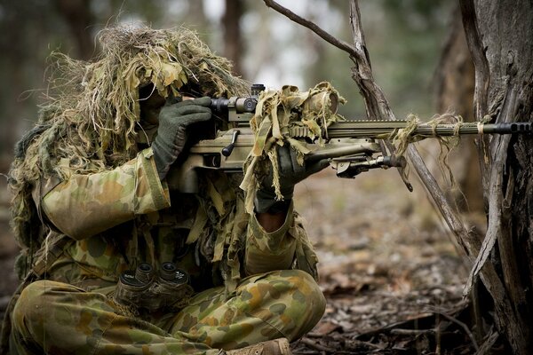 A soldier in a military uniform aims a machine gun