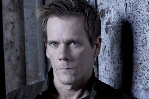 Portrait of Kevin Bacon against a gray wall