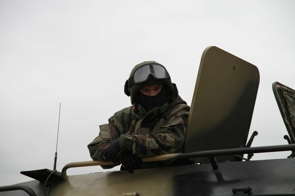 A soldier in uniform looks out of a tank